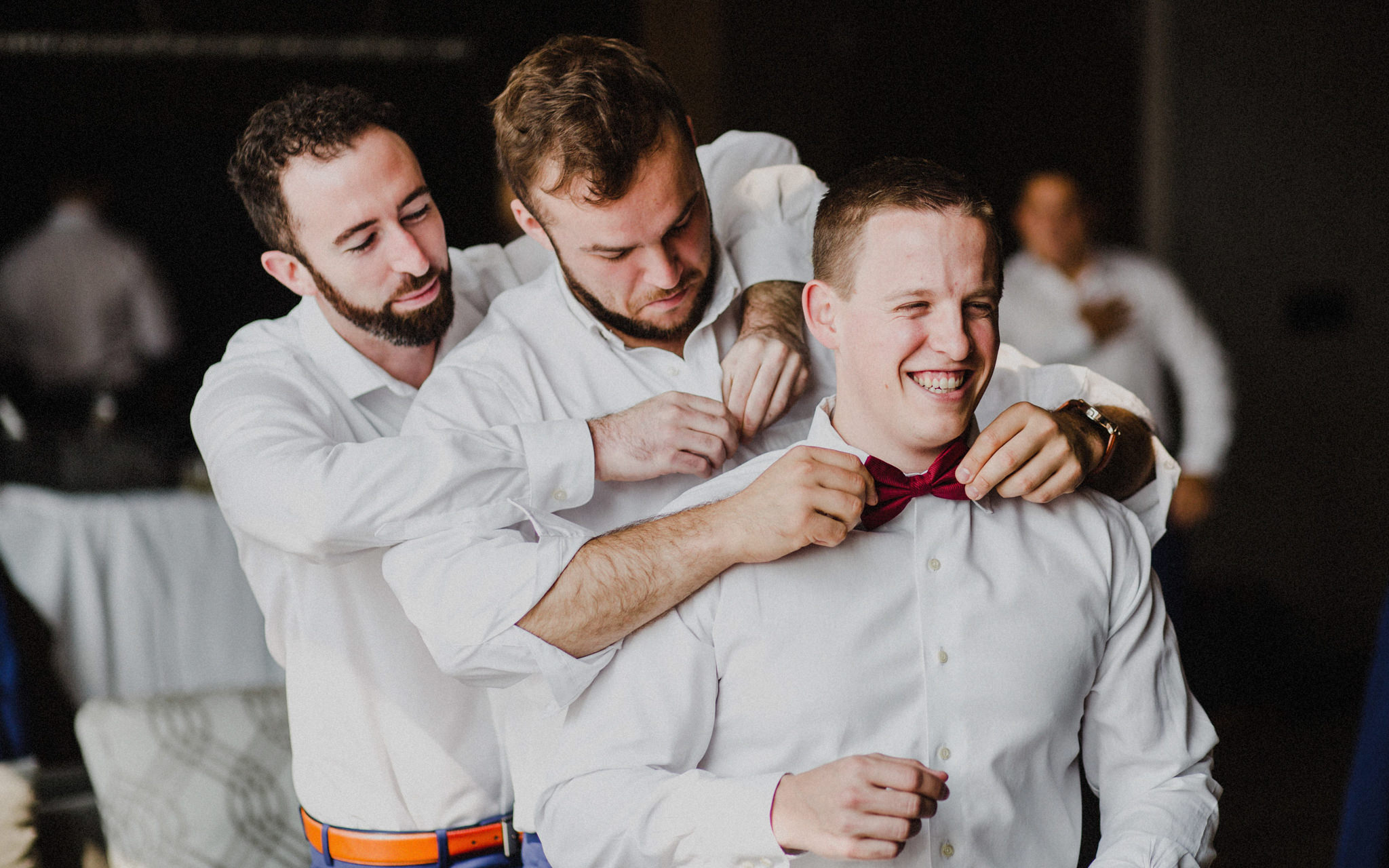 groomsmen help groom get ready