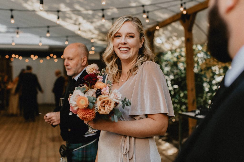 Bridesmaid smiles with bouquet - Autumn Micro Wedding at Berkeley Fieldhouse