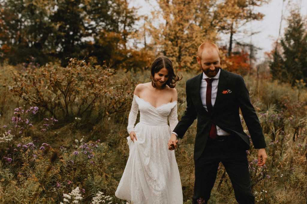Groom leads bride through wildflower field - Huron Natural Area Micro Wedding Kitchener, Ontario
