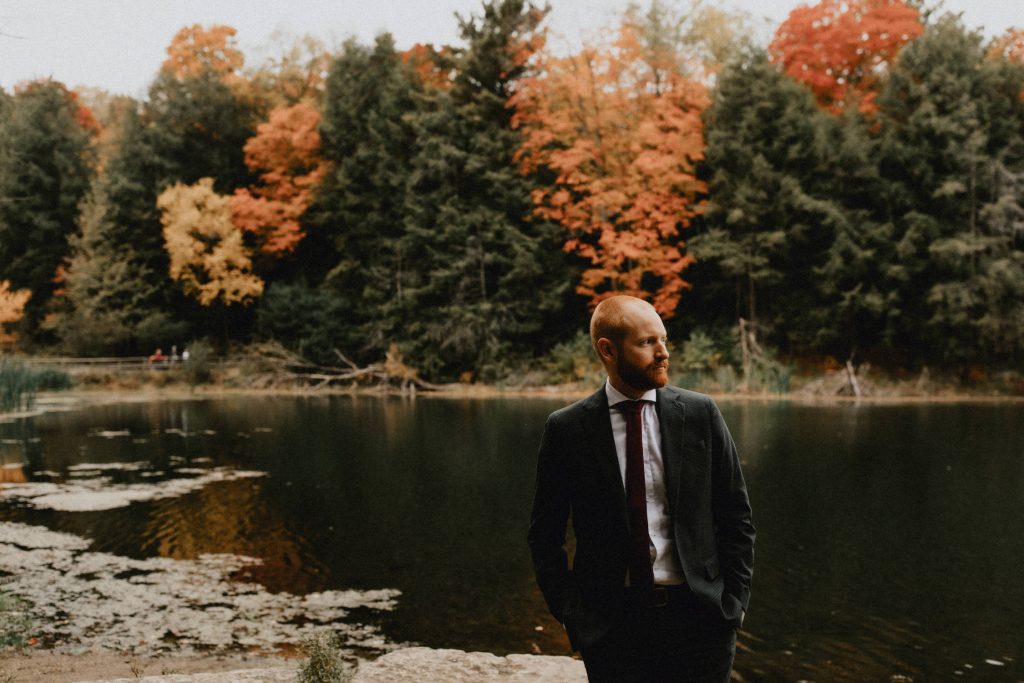 Groom near pond and fall trees - Huron Natural Area Micro Wedding Kitchener, Ontario