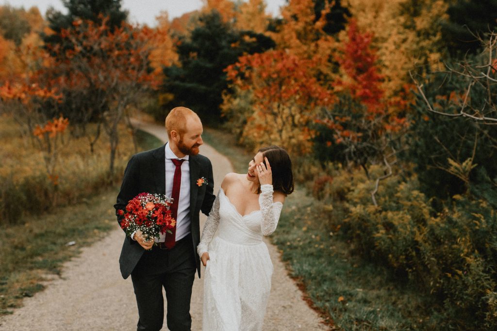 Bride and groom walk through park in fall - Huron Natural Area Micro Wedding Kitchener, Ontario