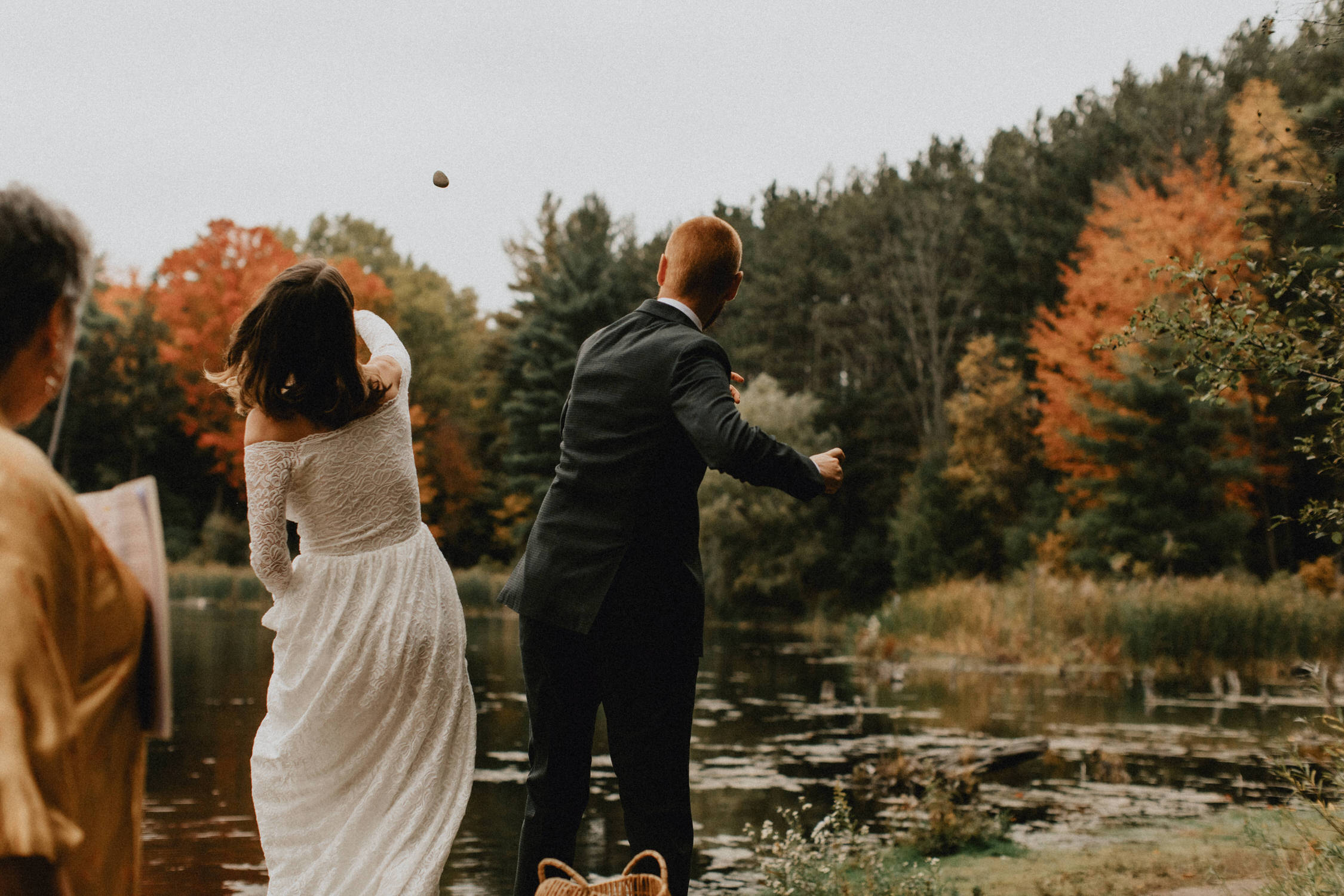 Bride and groom throw rocks in the pond to make a wish - Huron Natural Area Micro Wedding Kitchener, Ontario